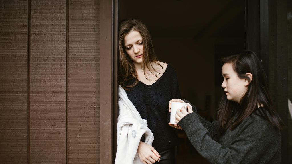 Una mujer le lleva una taza de café a otra