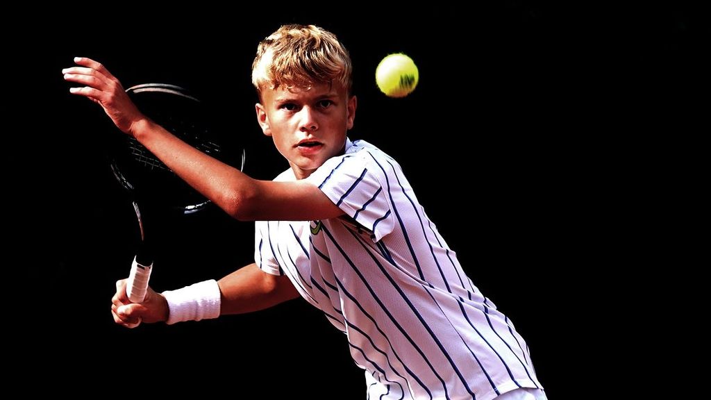 Un niño juega al tenis