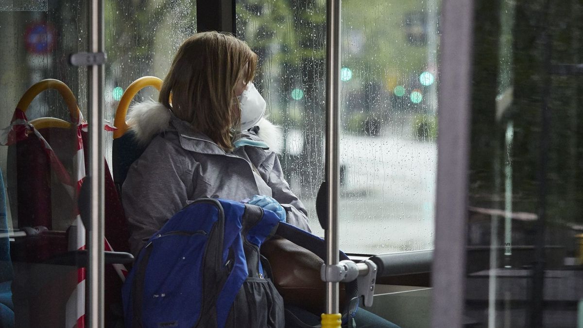 Una mujer con mascarilla en un autobús urbano.