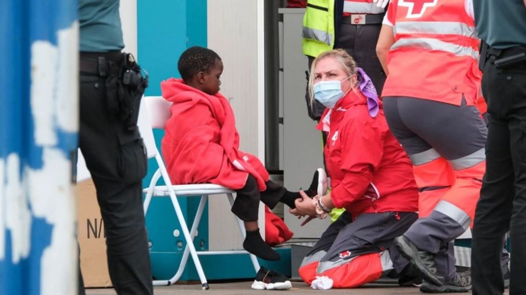 Una voluntaria de Cruz Roja atiende en el puerto de Los Cristianos (Tenerife) uno de los niños rescatados de un cayuco con 91 ocupantes..