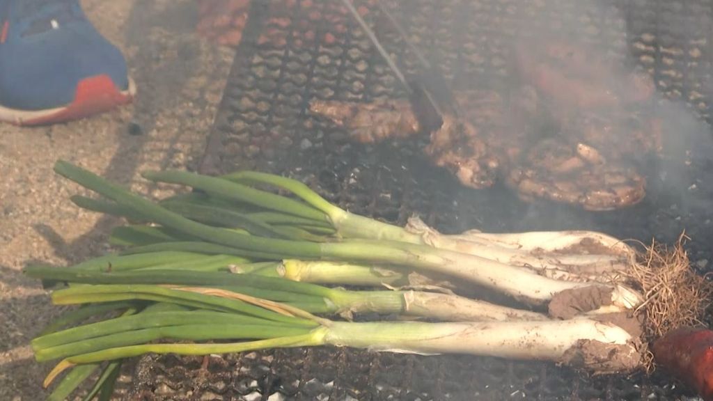 Calçots asándose junto a carnes en Valls, Tarragona