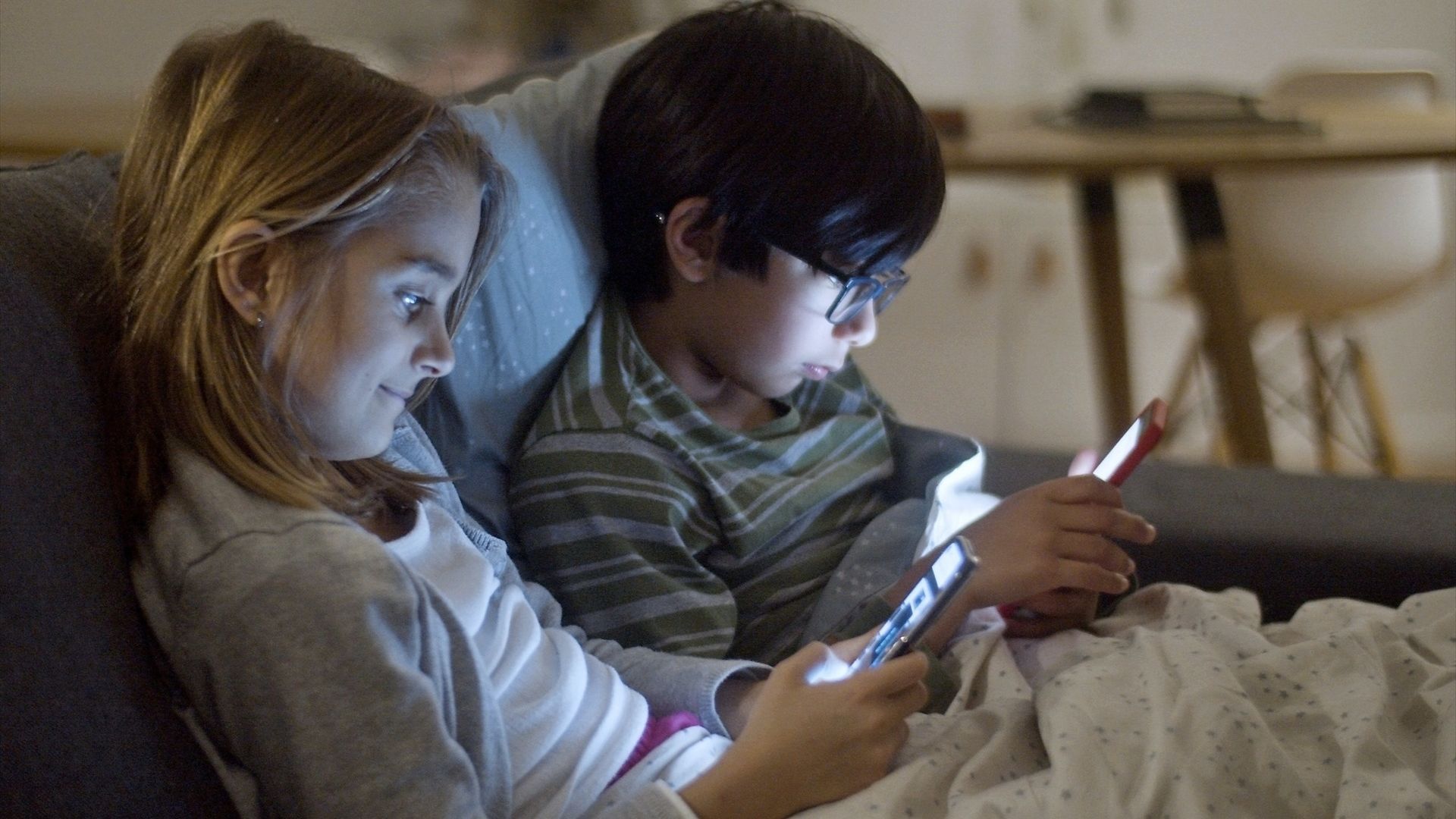 La imagen de dos menores utilizando dispositivos móviles.