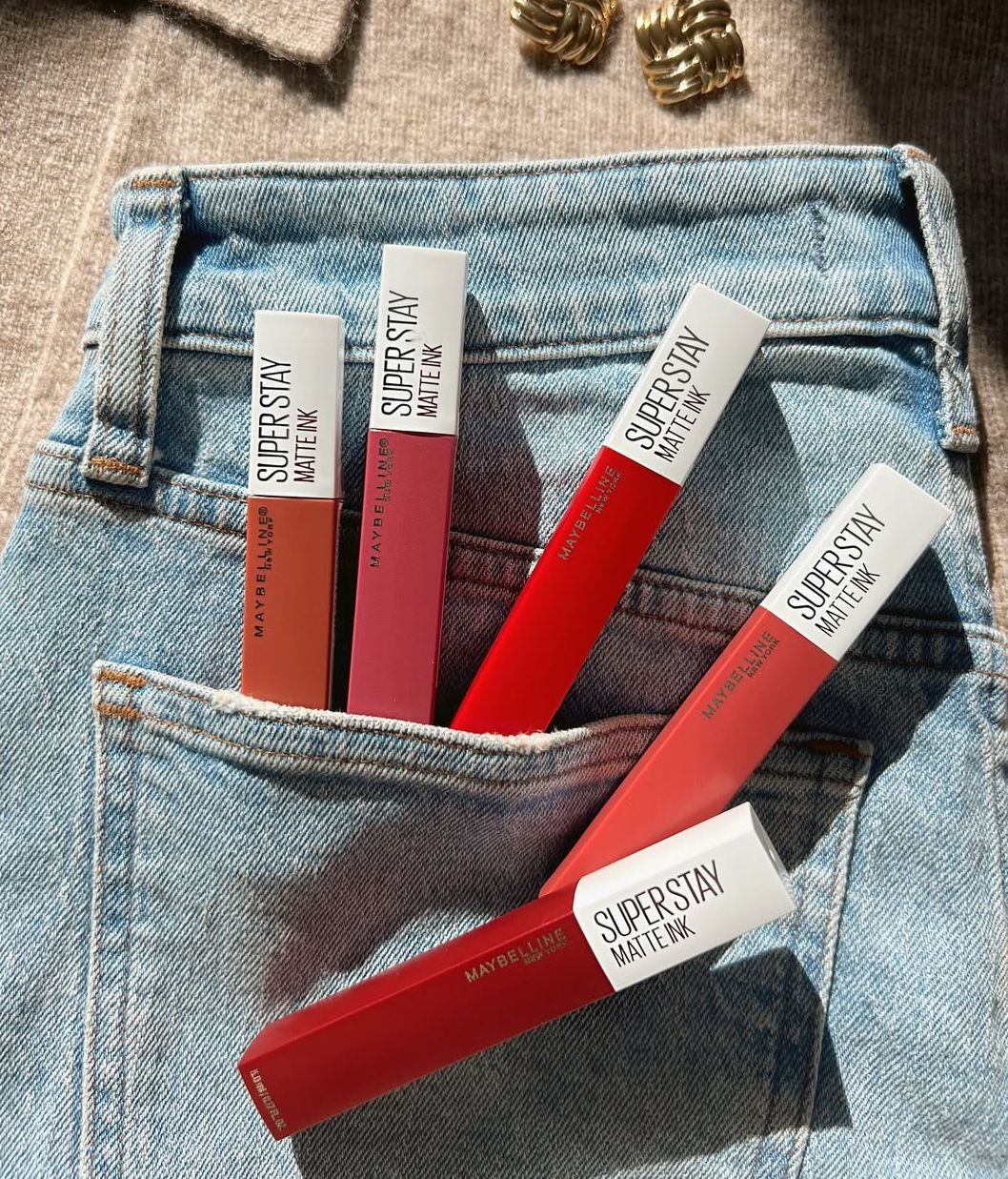 Varios labiales SuperStay Matte Ink sobre un pantalón vaquero