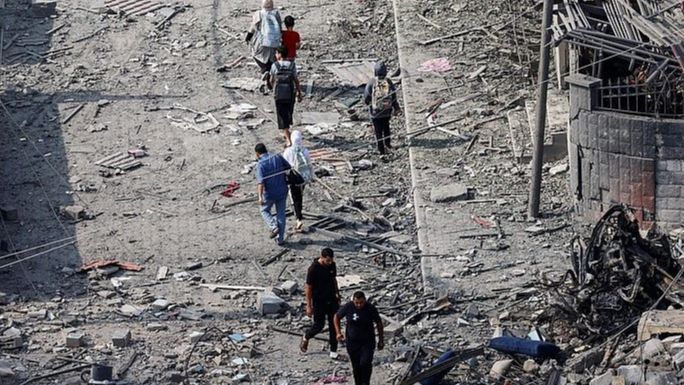 Gazatíes caminan entre las ruinas de sus casas y calles en la Franja.