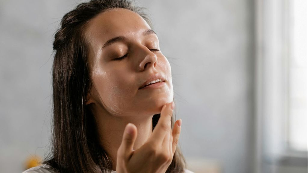 Mujer aplicándose crema en el rostro