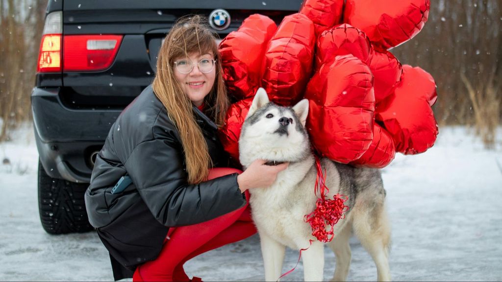 Una mujer y su perro, atado con globos en forma de corazón