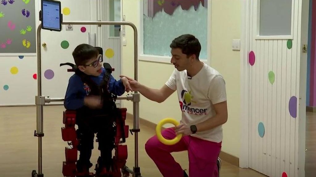 El fisioterapeuta Pablo García con Hugo y su exoesqueleto.
