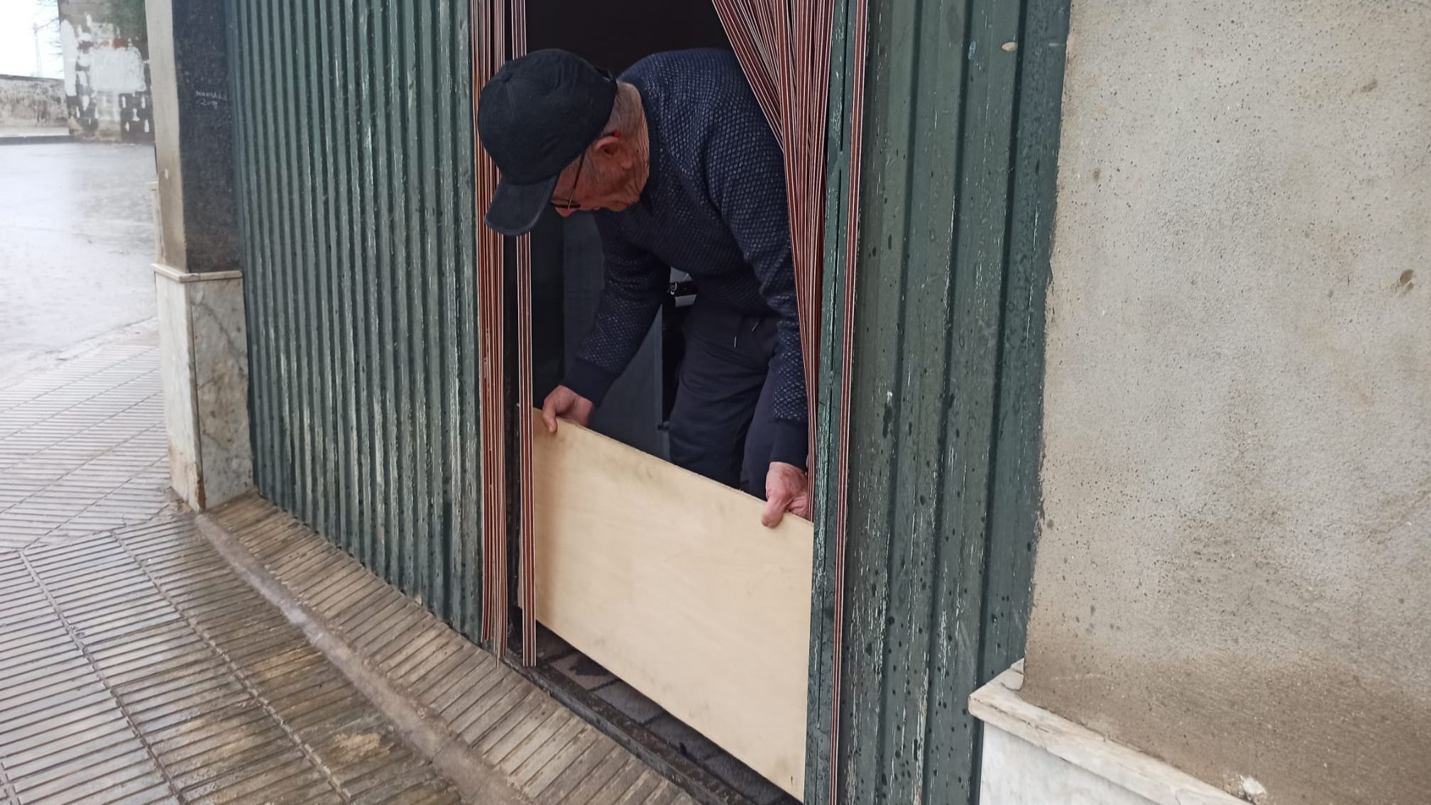 Un hombre pone una madera en la puerta de su casa