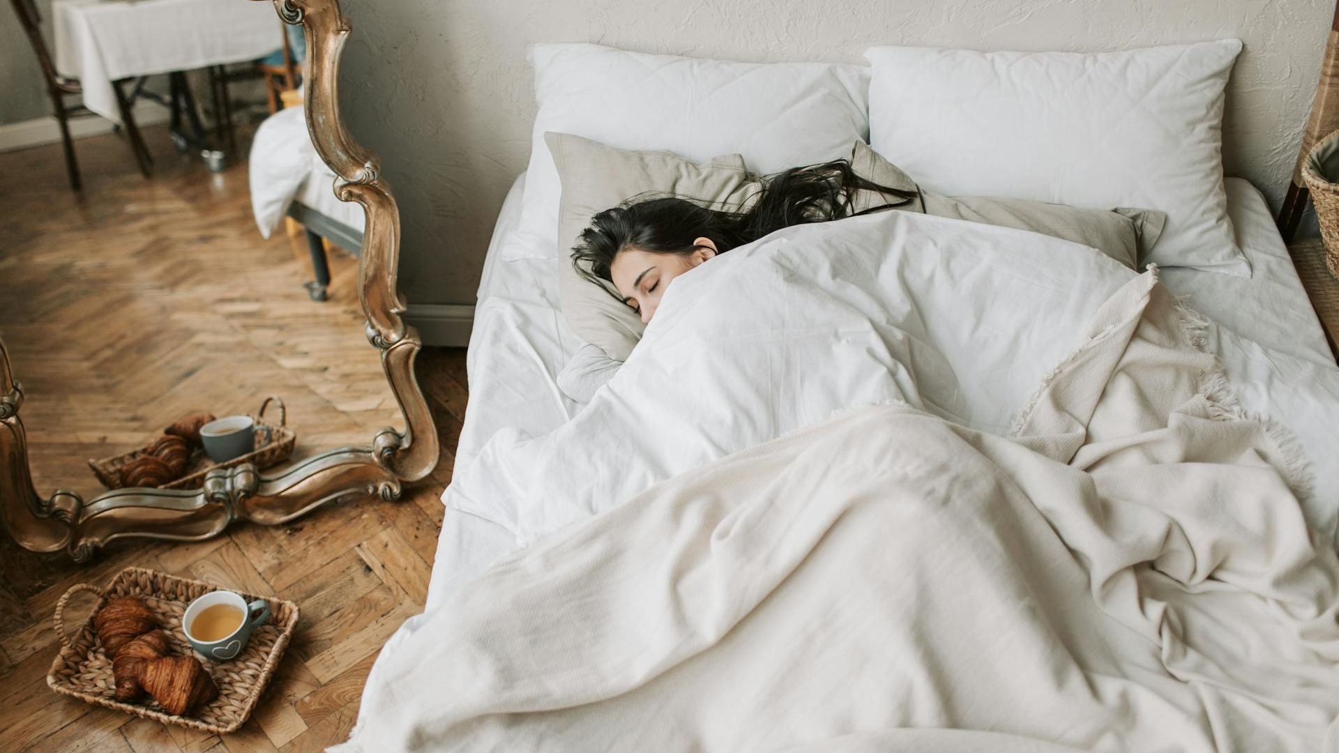 Una mujer descansa en cama mientras le espera el desayuno en una bandeja Una mujer descansa en cama mientras le espera el desayuno en una bandeja