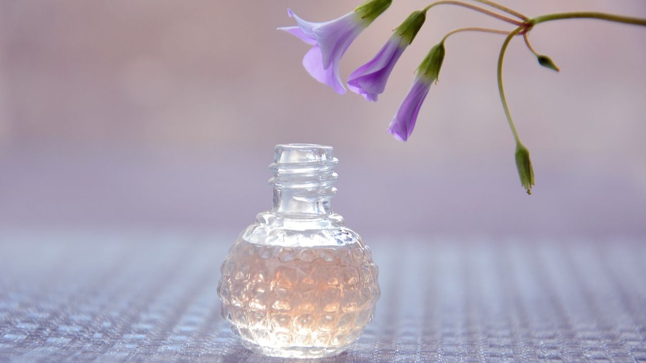 Frasco de perfume junto a unas flores