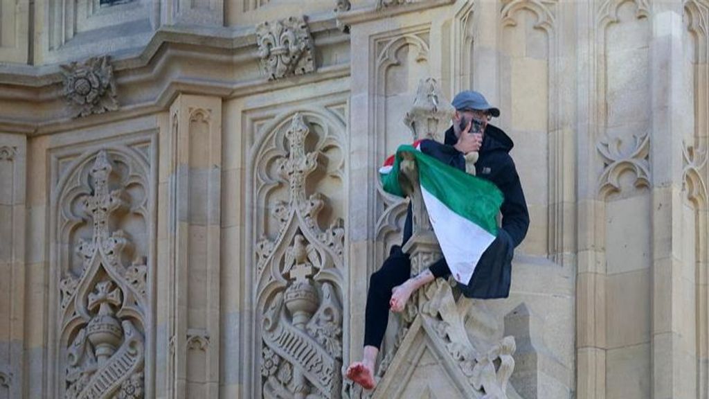 Un hombre enarbolando la bandera palestina encaramado al Big Ben