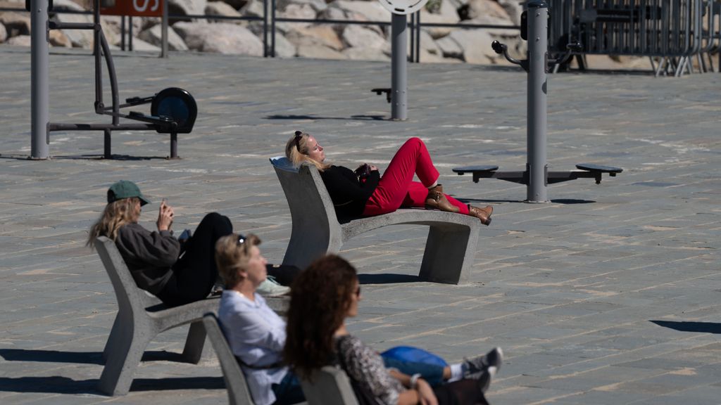 Varias personas toman el sol en el Paseo marítimo de Barcelona