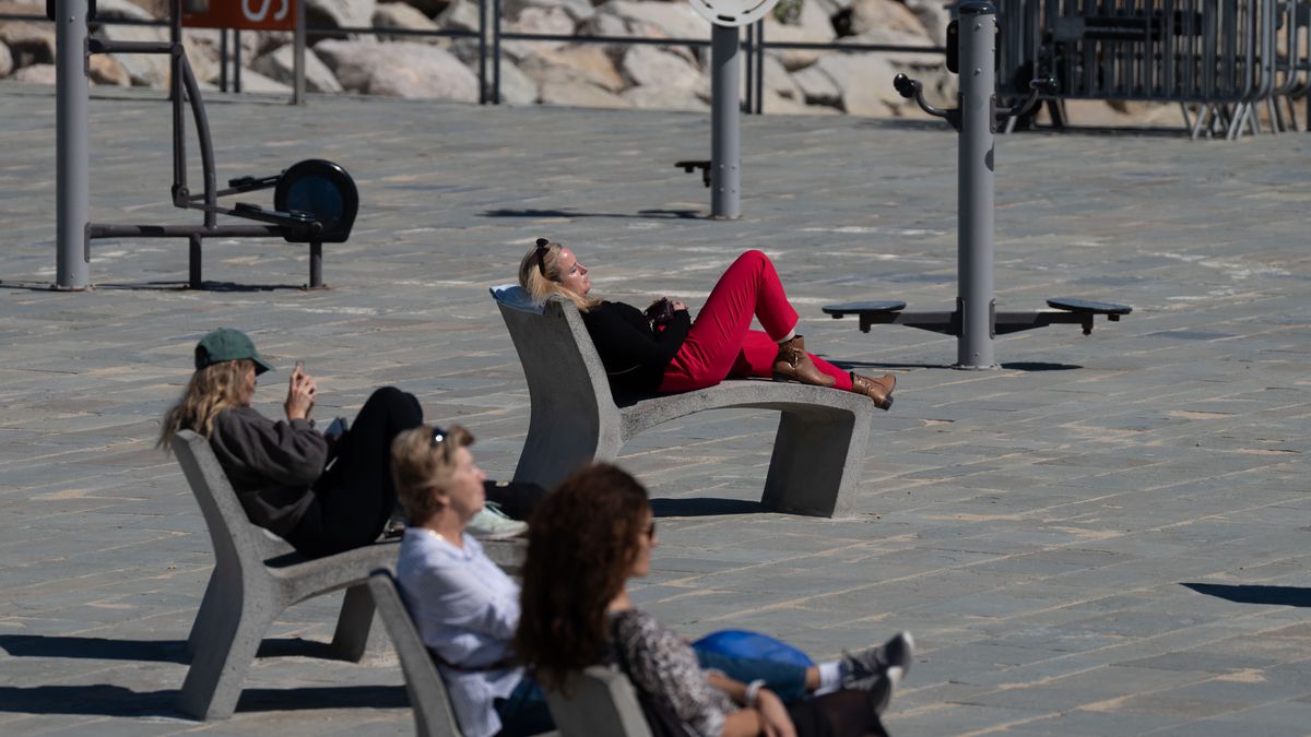 Varias personas toman el sol en el Paseo marítimo de Barcelona