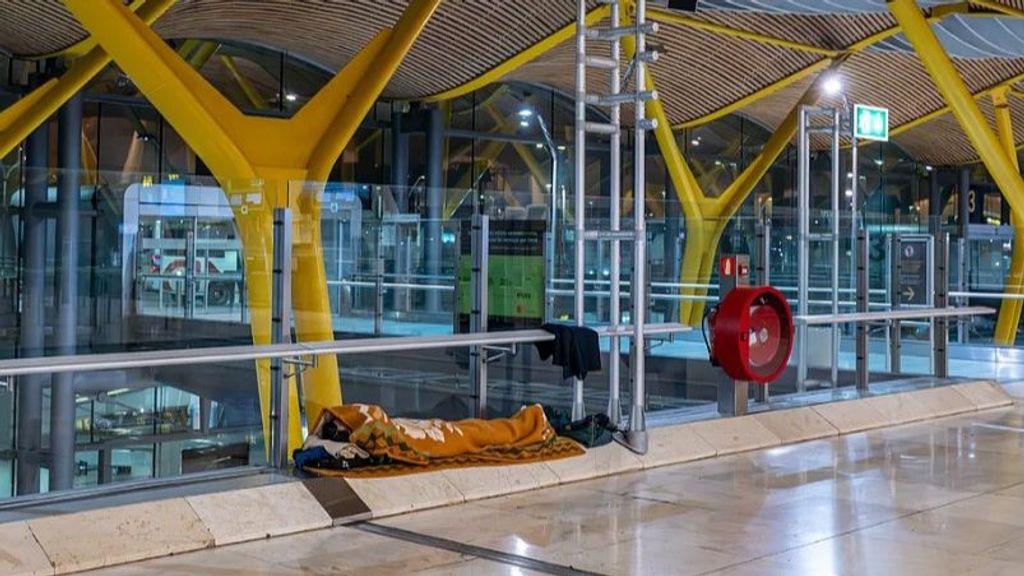 Una persona duerme en un pasillo del aeropuerto de Madrid en Barajas.