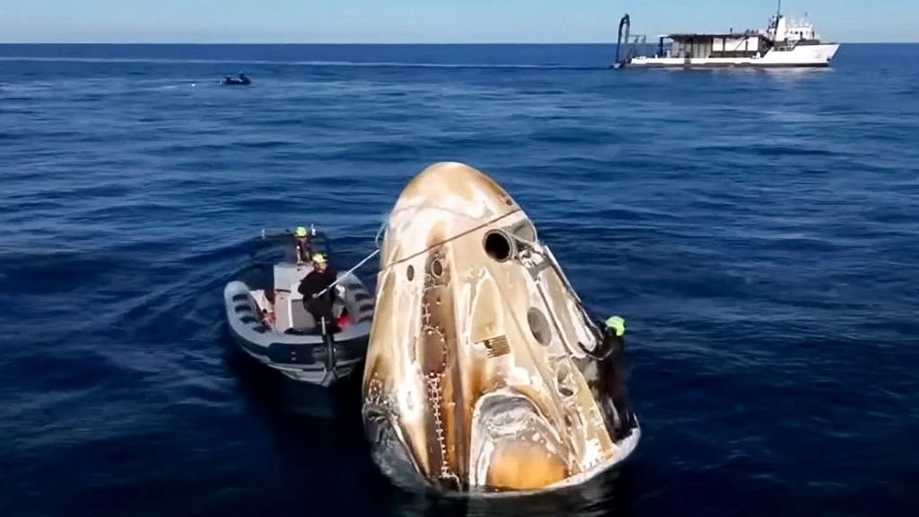Captura de un fotograma del vídeo retransmitido en directo por la NASA de la cápsula Crew Dragon de SpaceX rodeada por los equipos de recuperación tras amerizar frente a la costa de Tallahassee, Florida