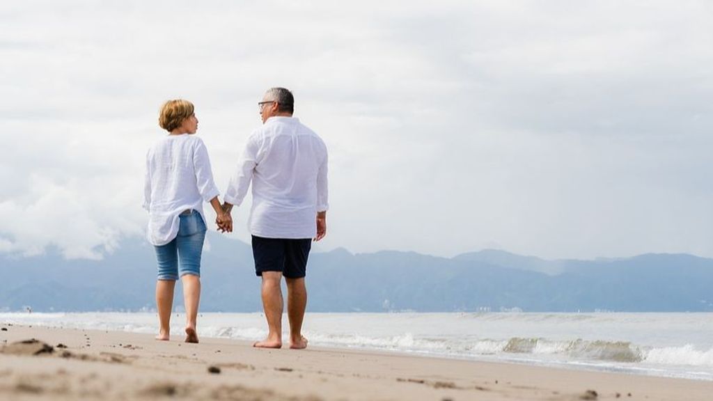 Una pareja camina por la playa de la mano