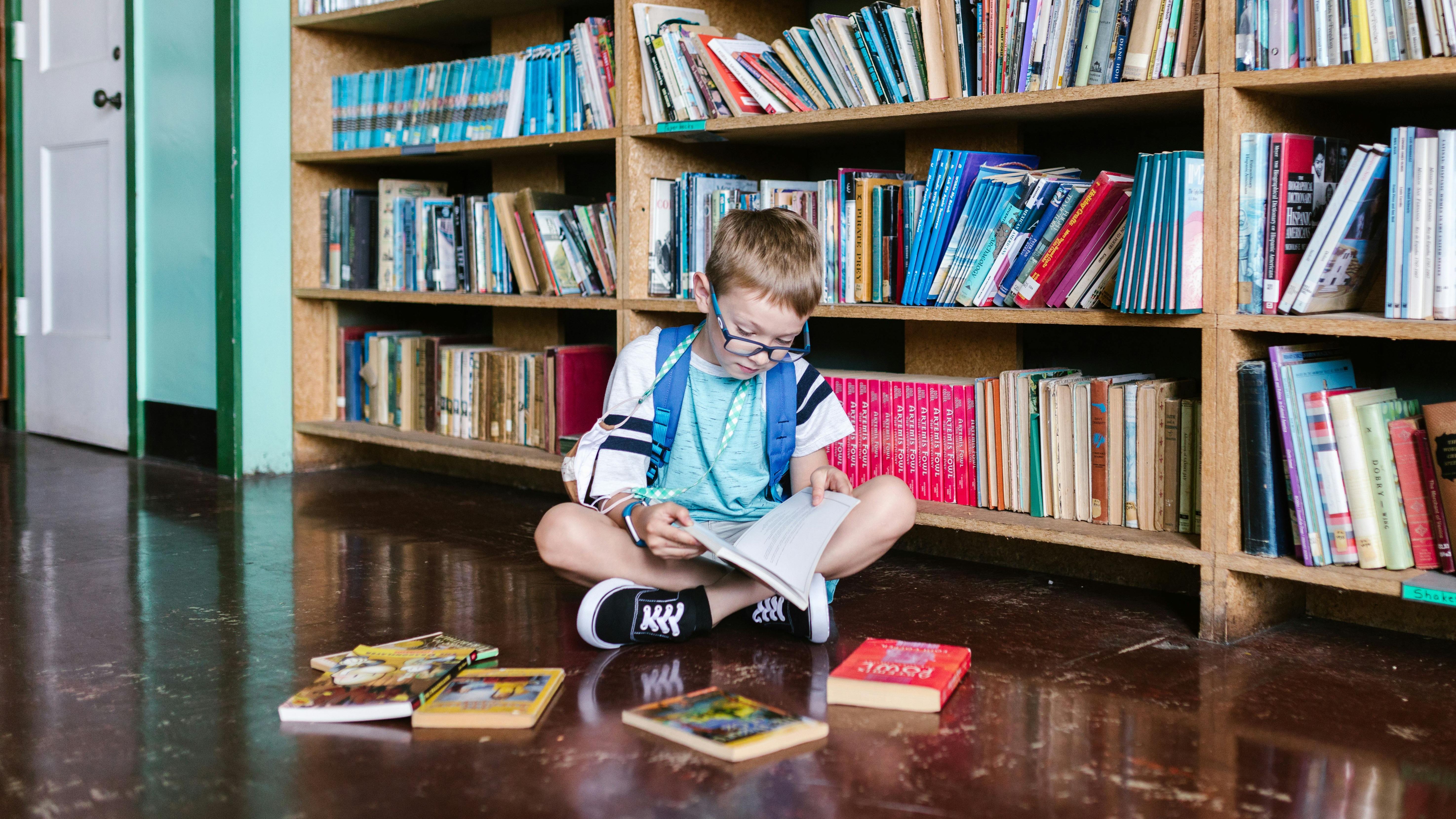 Niño leyendo un libro en una biblioteca
