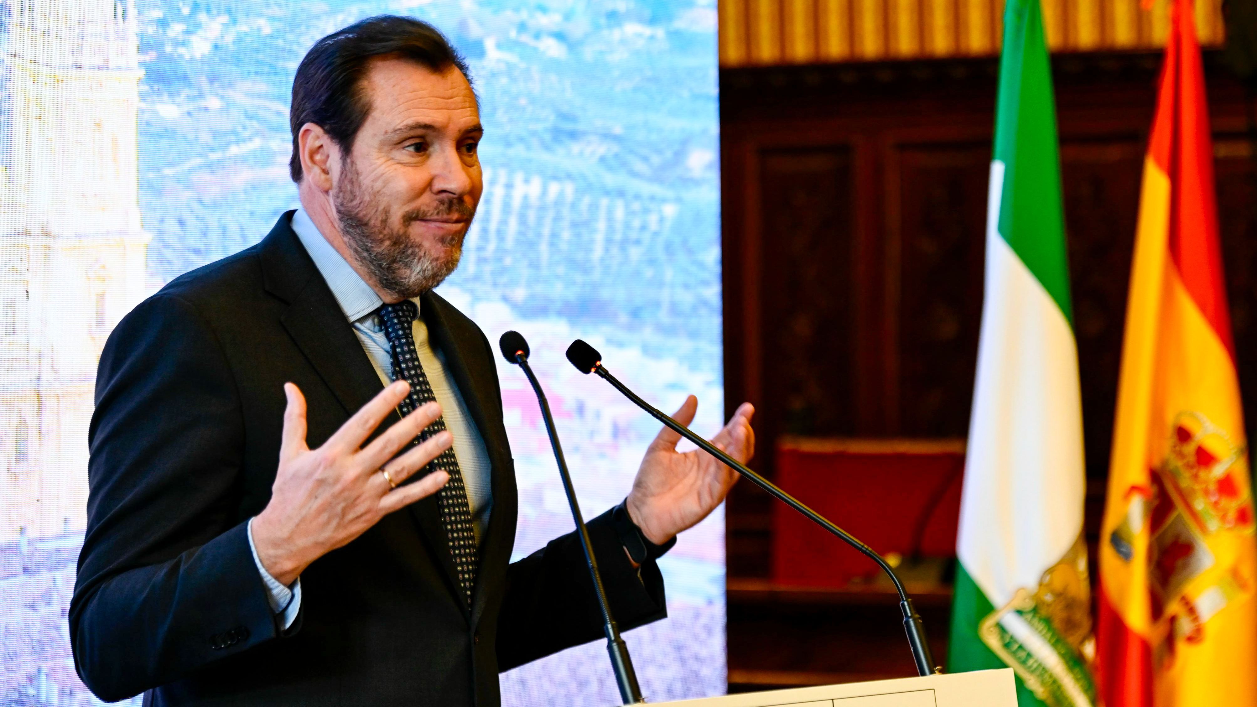 Óscar Puente hablando en un atril junto a las banderas de Andalucía y España