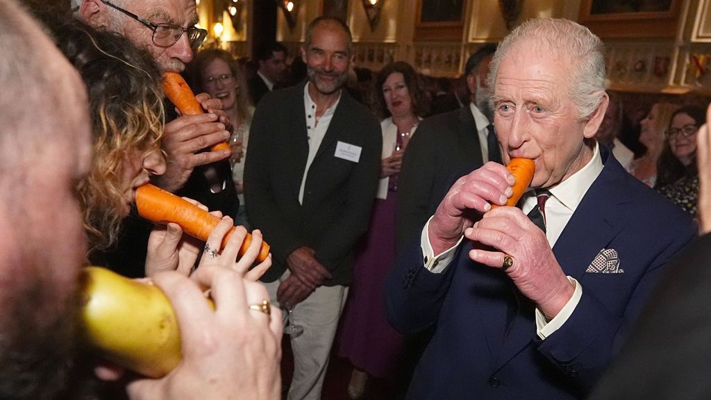 El rey Carlos III tocando la flauta con forma de zanahoria.