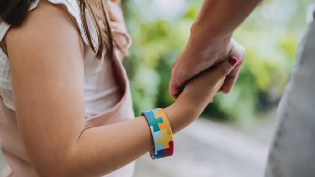 Una niña con autismo da la mano a su madre
