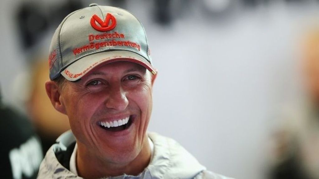 Michael Schumacher firma un casco del tricampeón de F1 Jackie Stewart con la ayuda de su esposa y para una causa solidaria