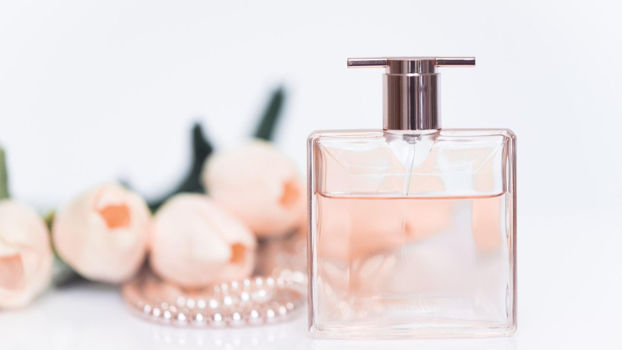 Frasco de perfume con rosas al fondo Frasco de perfume con rosas al fondo