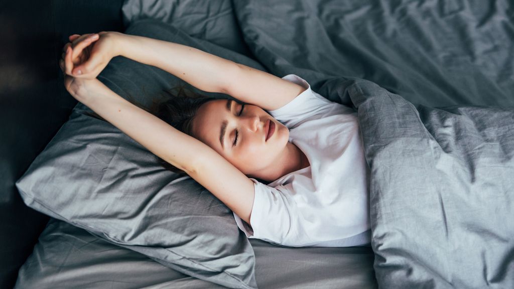 attractive woman stretching in the morning and is smiling in her bed