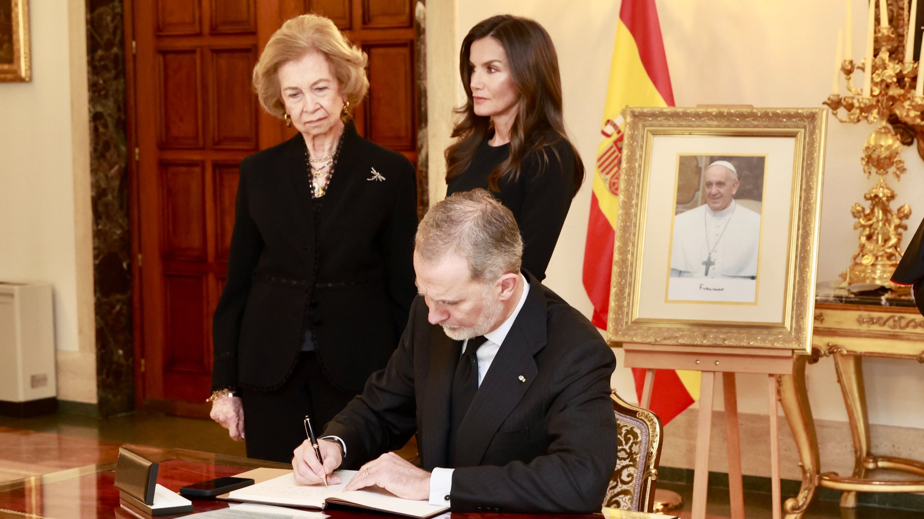 Los reyes y la emérita firmando en el libro de condolencias por la muerte del papa Francisco.