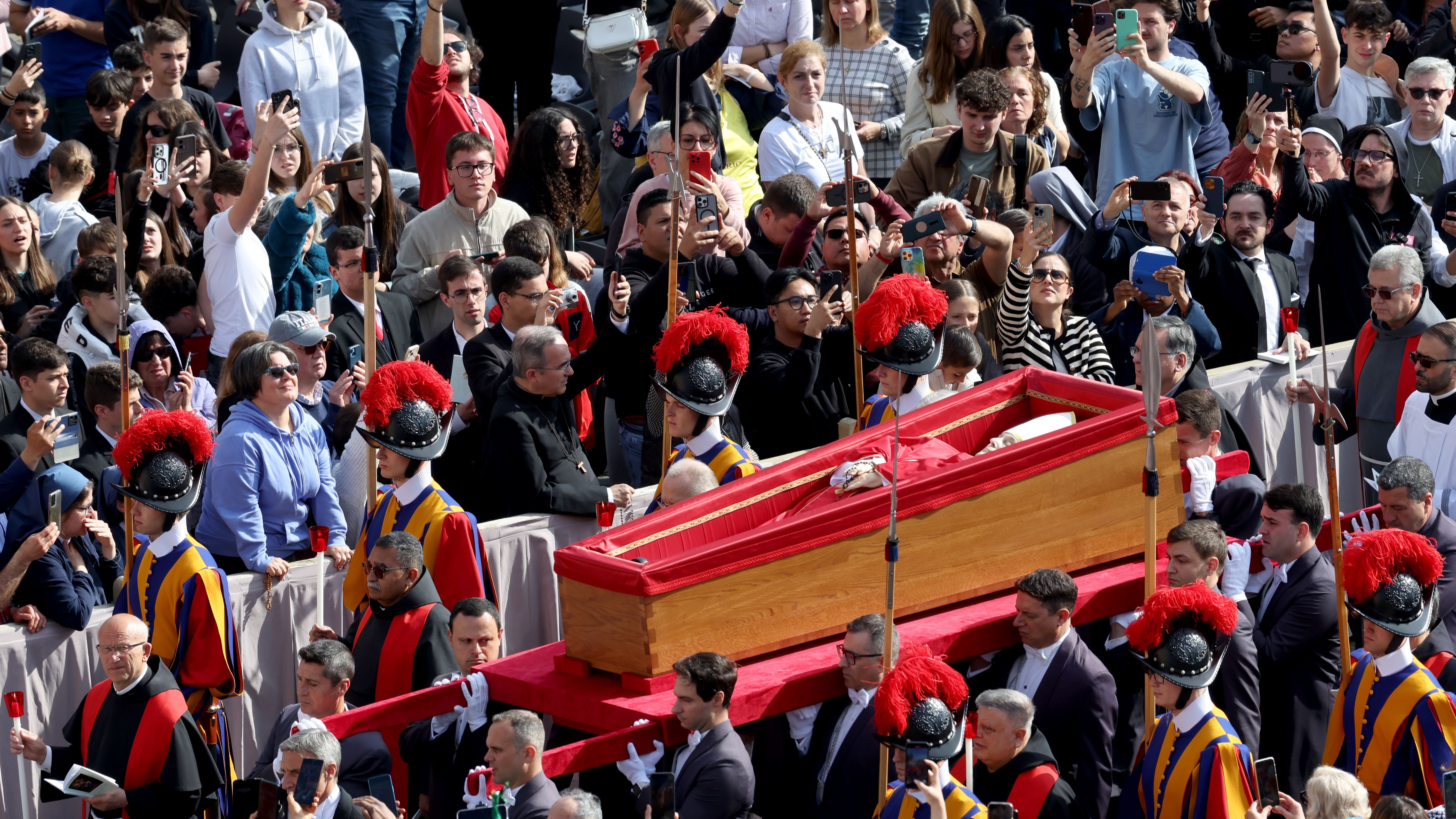 Los fieles tratan de captar el momento del paso del féretro del papa