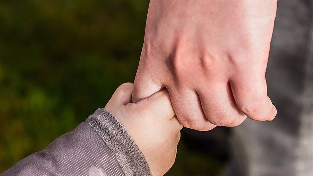 Niño de la mano de un adulto