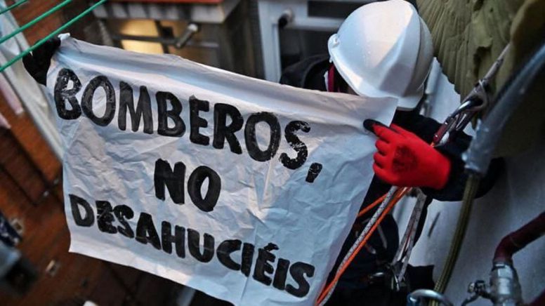 Militante del movimiento de vivienda descolgado por la fachada para evitar el desahucio de un vecino de Vallecas