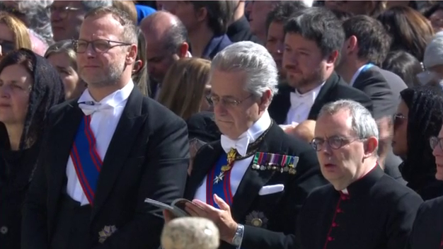 Uno de los asistentes al funeral del papa Francisco sostiene a un bebé en brazos