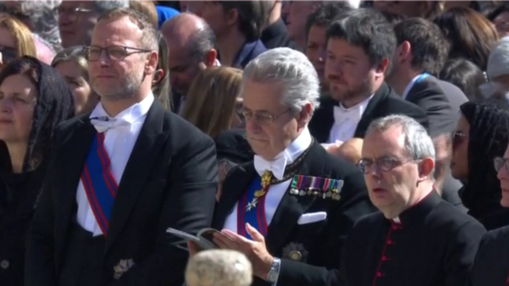 Uno de los asistentes al funeral del papa Francisco sostiene a un bebé en brazos