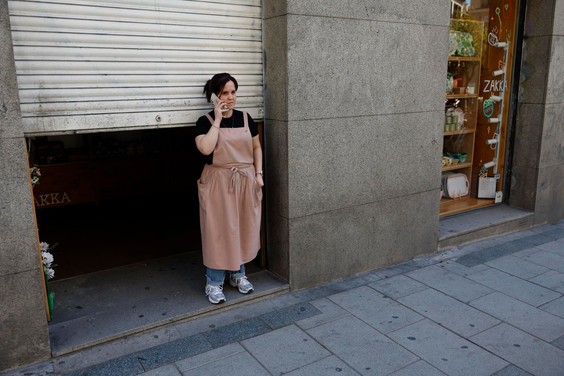 Una mujer, sin poder subir la puerta de su comercio