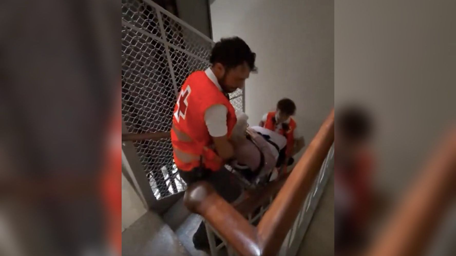 Voluntarios de la Cruz Roja suben a una persona mayor en silla de ruedas hasta su domicilio