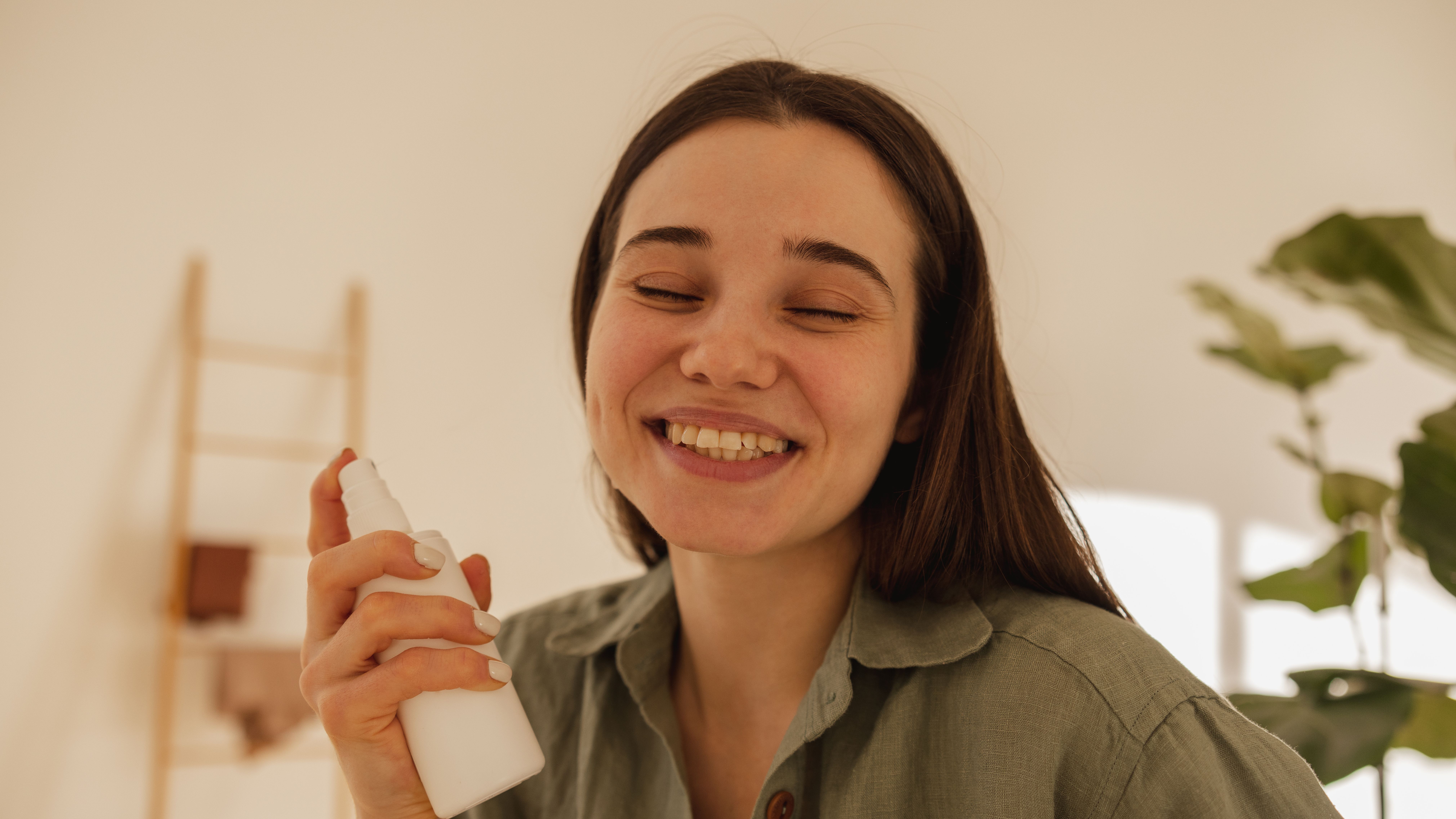 Mujer aplicándose un spray fijador en la cara Mujer aplicándose un spray fijador en la cara
