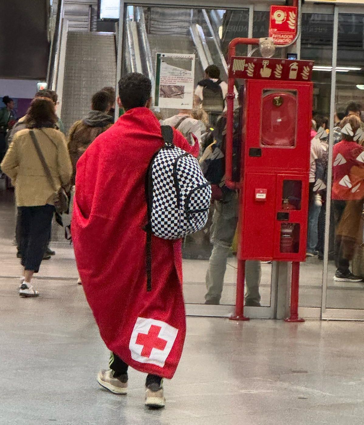 Una persona con una manta de la Cruz Roja en una estación de trenes de Madrid tras el apagón.
