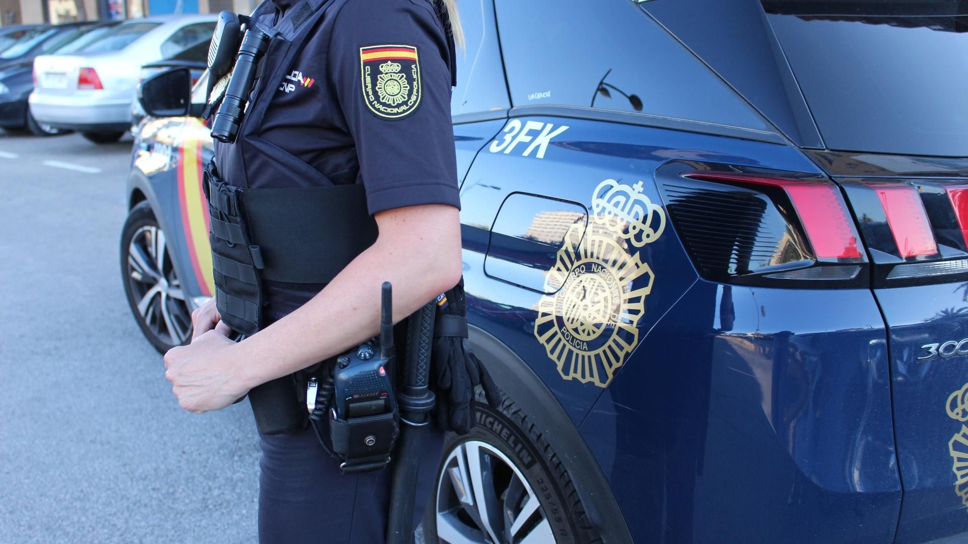 Imagen de una agente y de un coche patrulla de la Policía Nacional.