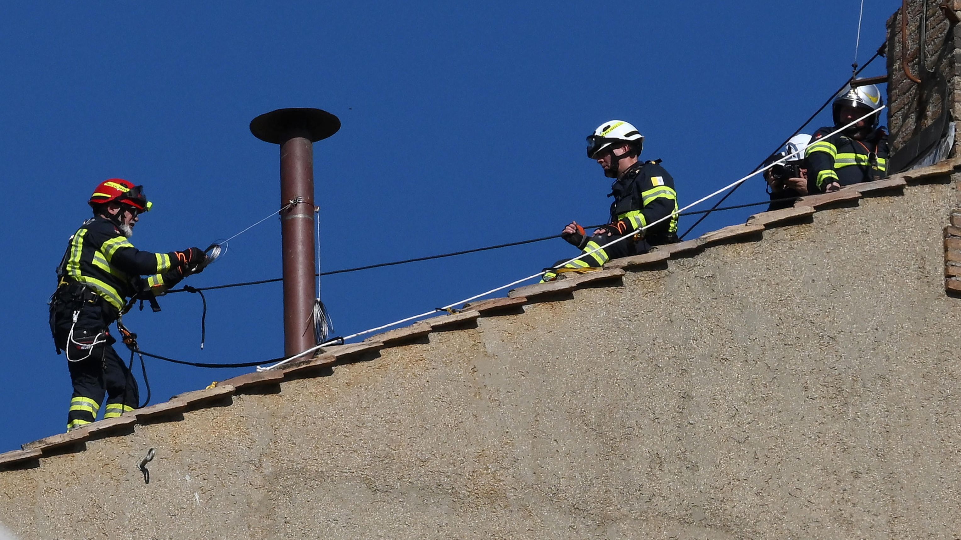 Los bomberos instalan la chimenea en la Capilla Sixtina que anunciará el nuevo papa.