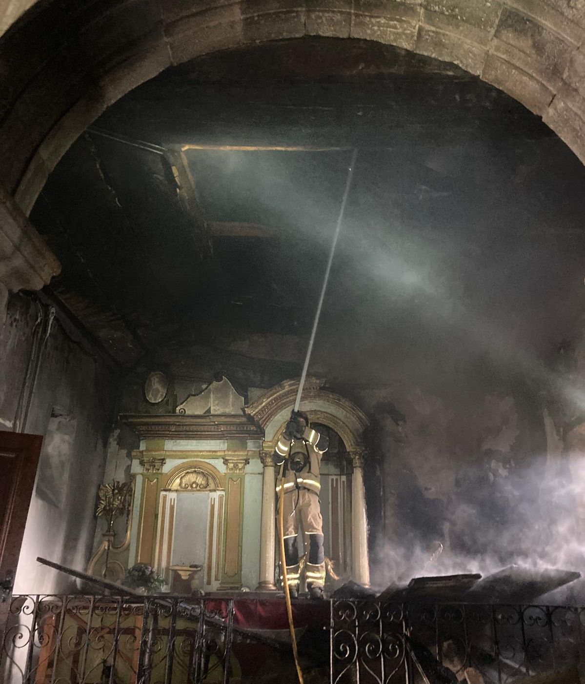 Bombero trabajando en el incendio de la iglesia de San Xiao de Carballo, en Friol