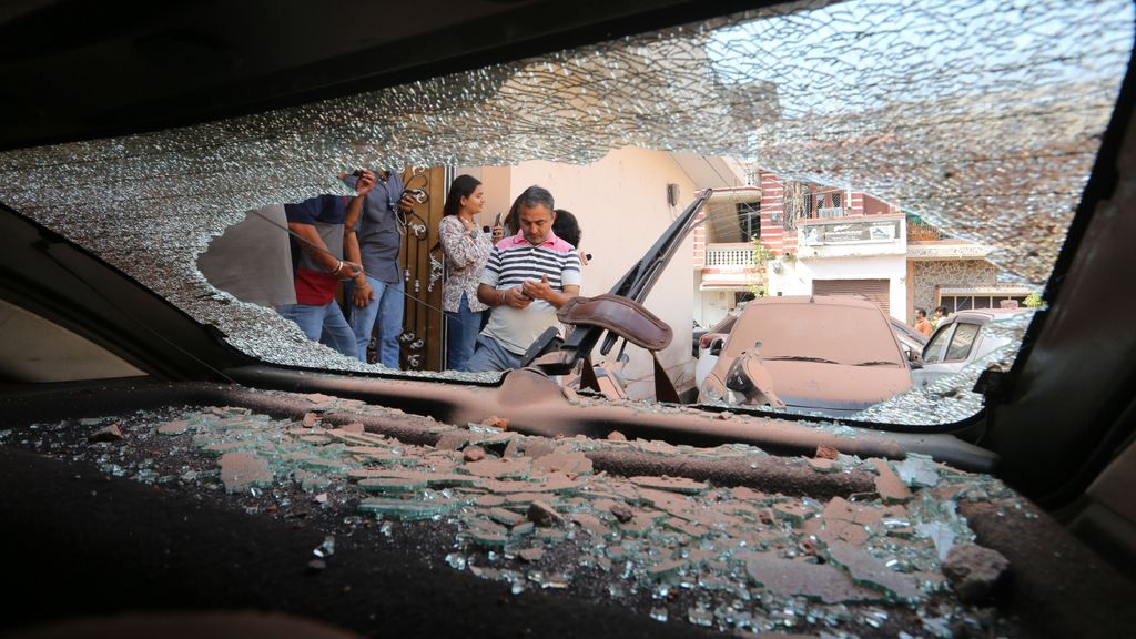 Ciudadanos indios se reúnen alrededor de un vehículo dañado tras un bombardeo transfronterizo procedente de Pakistán