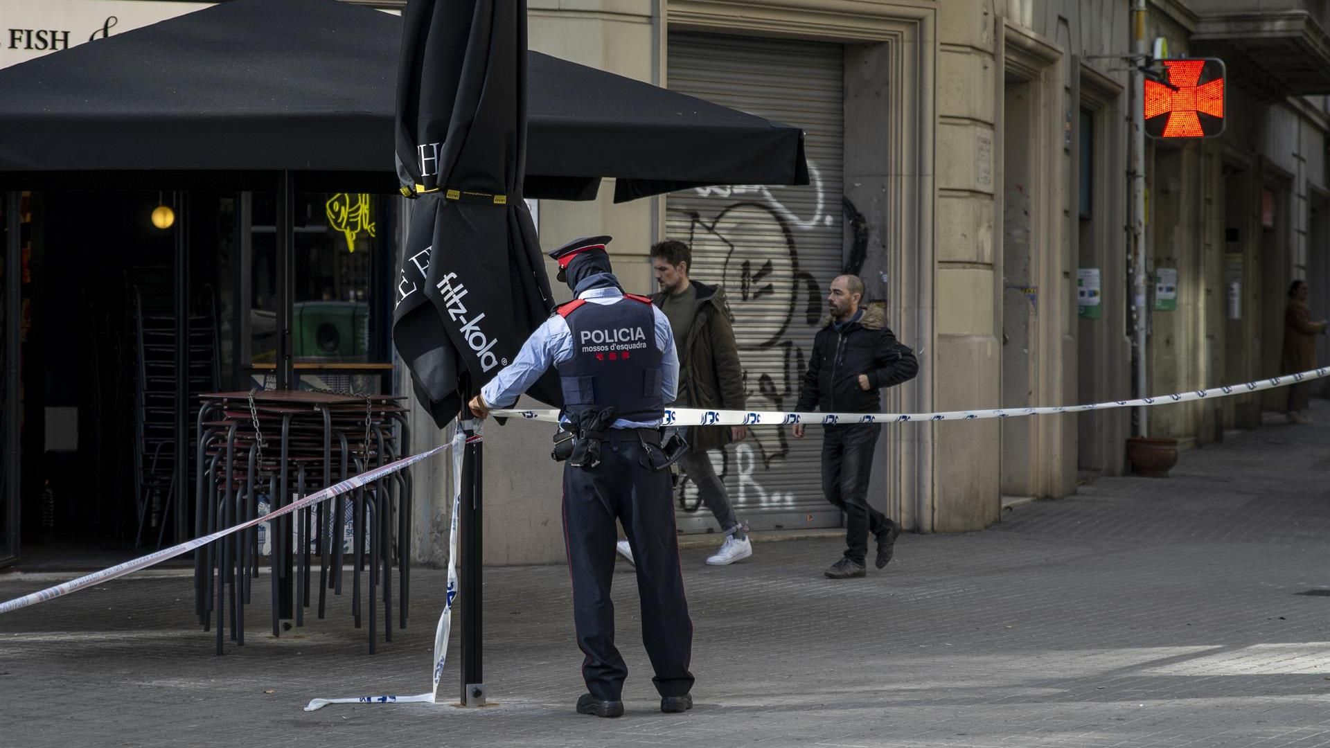 Un agente de los Mossos d'Esquadra acordona la zona donde encontraron un cadáver en un contenedor del centro de Barcelona