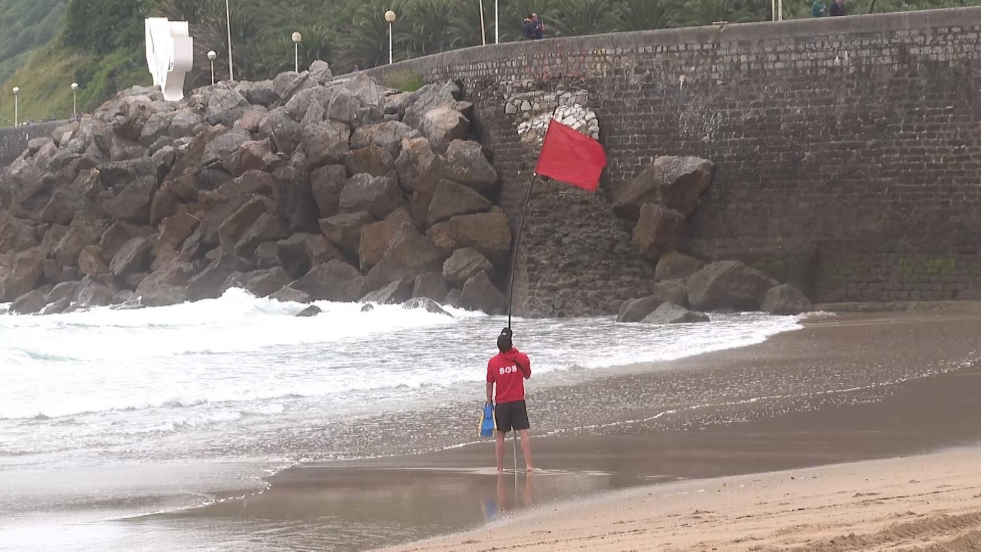 Un socorrista coloca la bandera roja en la playa donostiarra de La Zurriola.