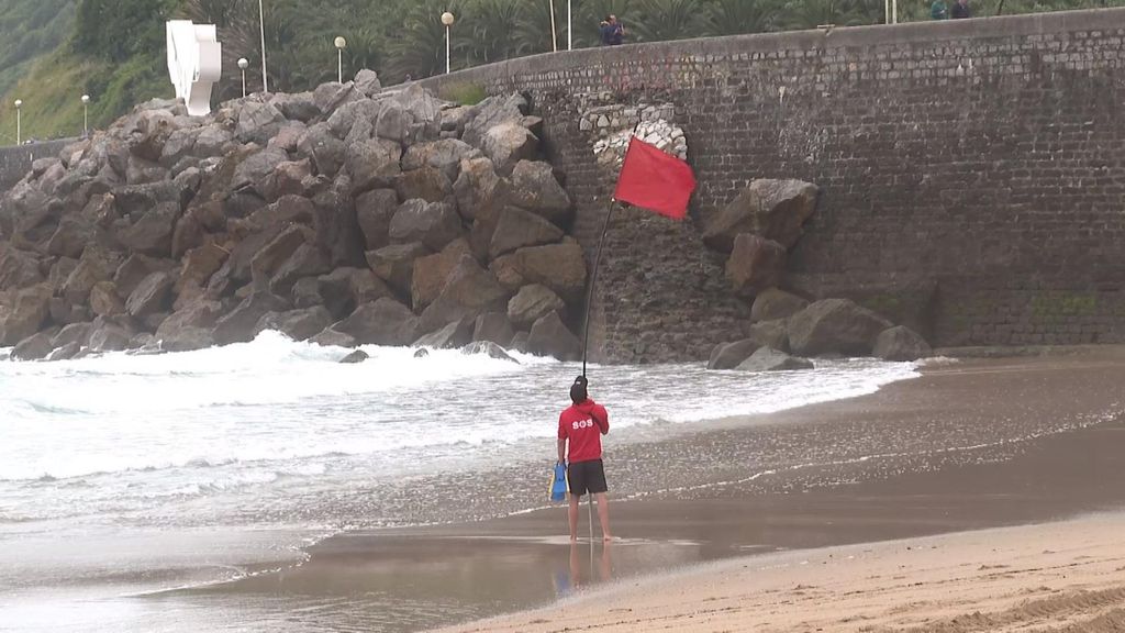 Un socorrista coloca la bandera roja en la playa donostiarra de La Zurriola.