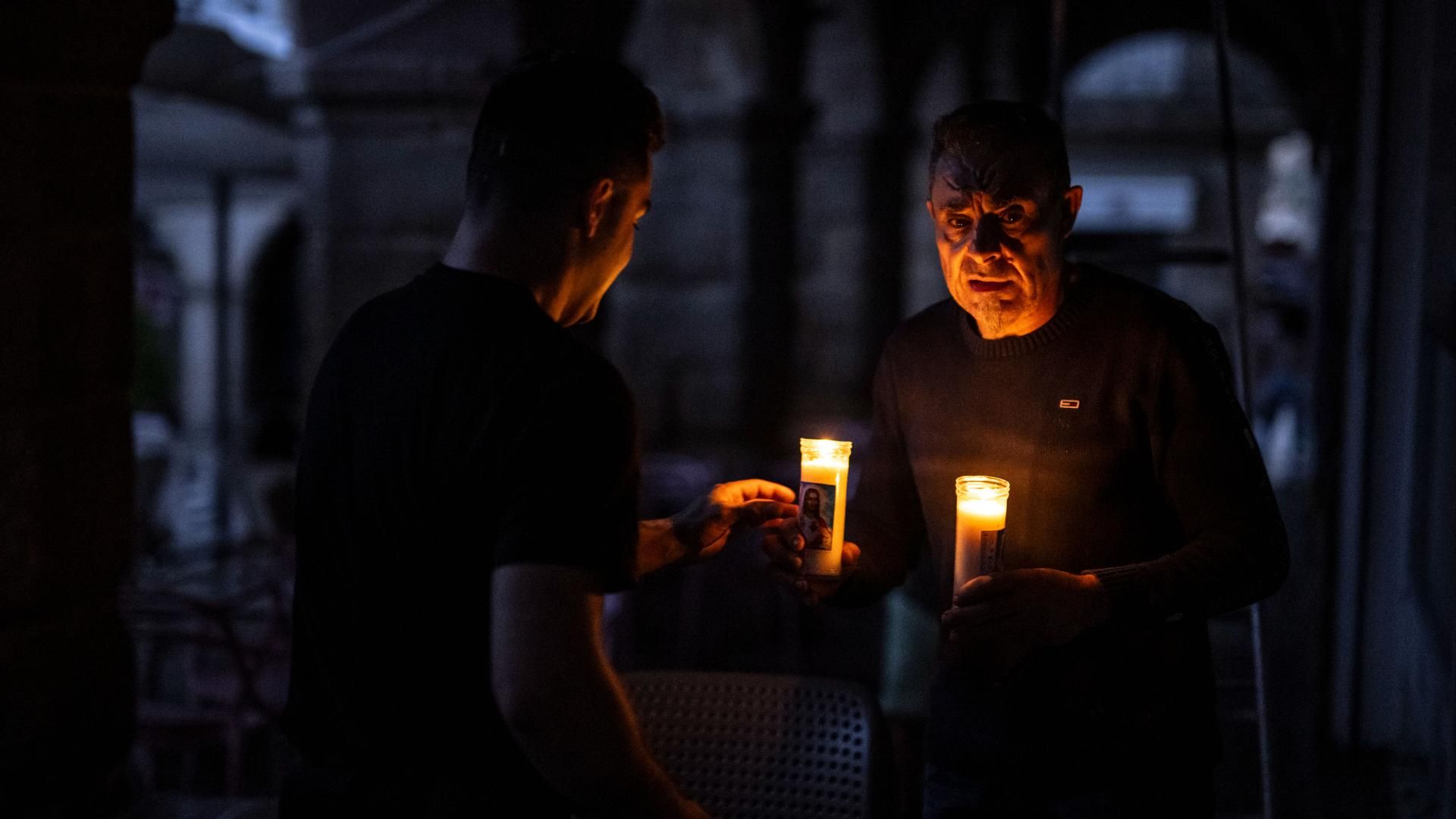 Dos personas iluminadas por la luz de las velas al caer la noche durante el apagón eléctrico en Ourense.
