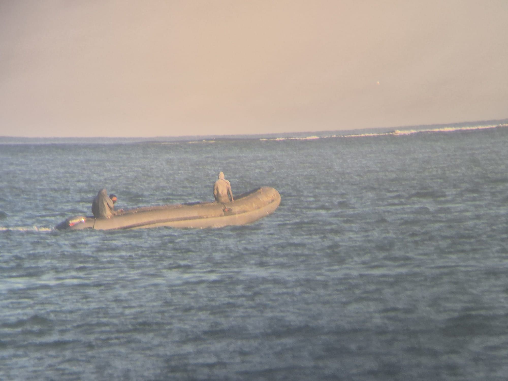 Tres tripulantes en una embarcación semirígida esperando para respostar en aguas de Chiclana de la Frotera, en Cádiz