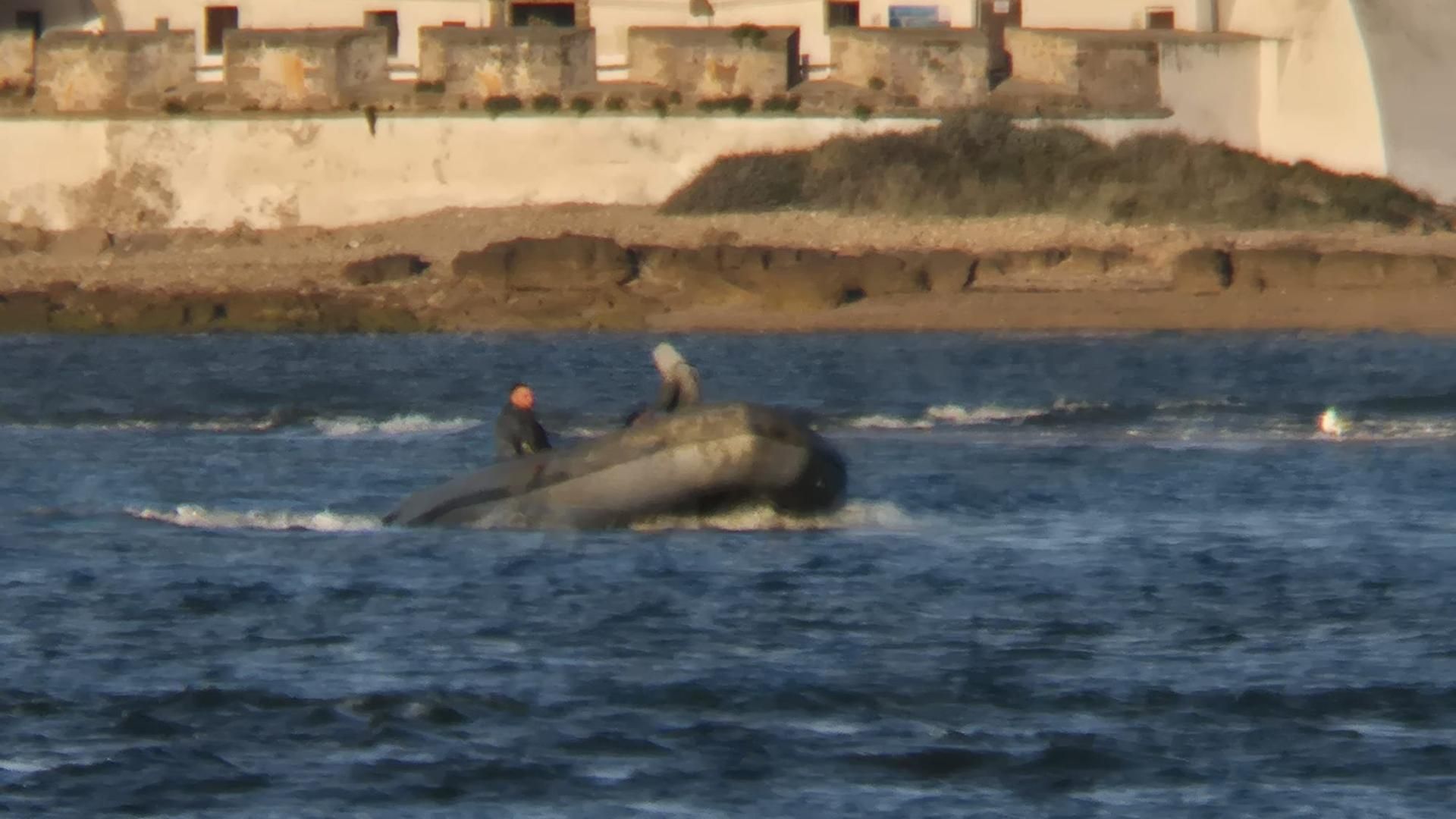 Tres tripulantes en una embarcación semirígida esperando para respostar en aguas de Chiclana de la Frotera, en Cádiz