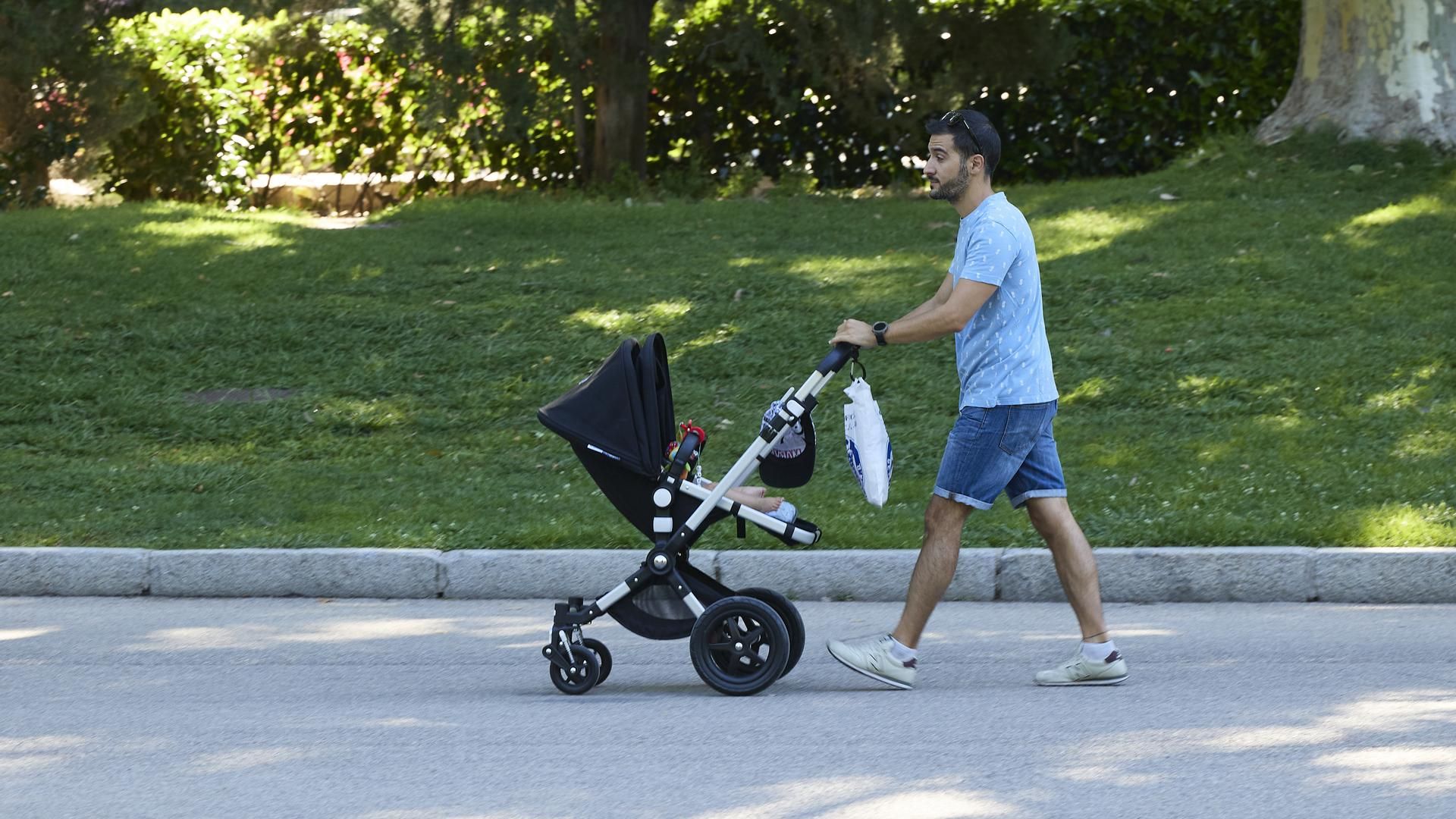 Una persona pasea con un carrito de bebé en el parque de El Retiro, Madrid