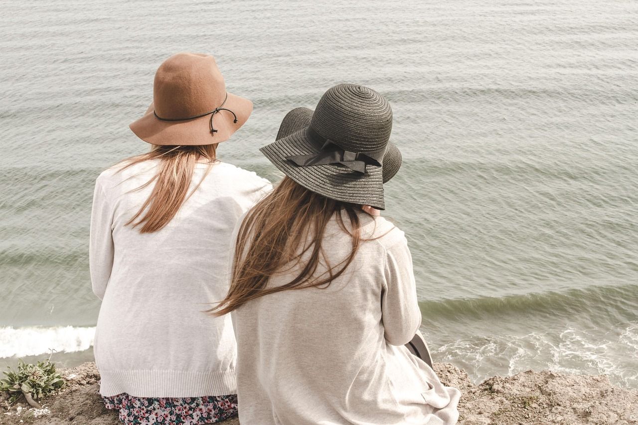 Dos mujeres usan sombrero en verano, clave para protegerse del sol y cuidar el cabello