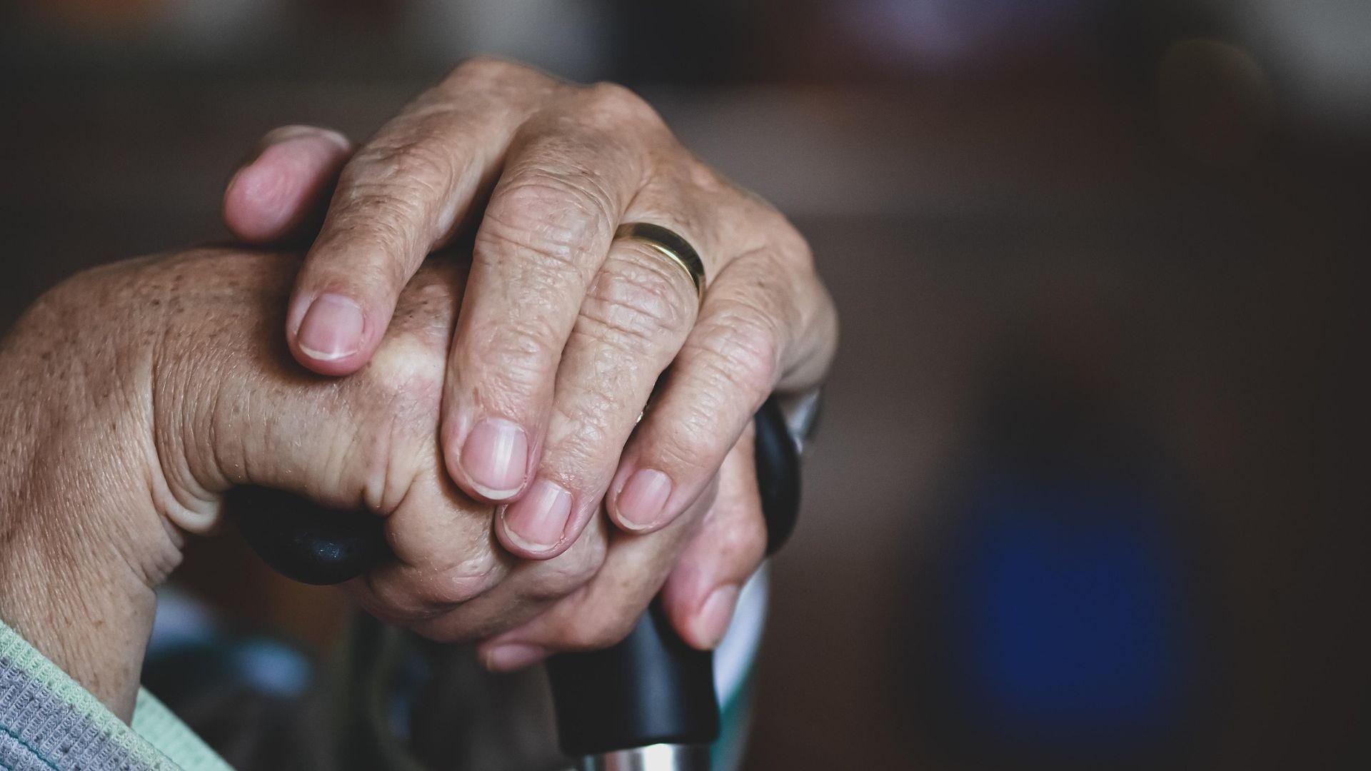 Manos de un anciano con un bastón